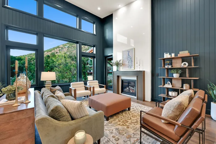 Living room featuring a tall ceiling, extensive windows, a gas fireplace with a surround, a built-in shelving unit, and wood-finish flooring