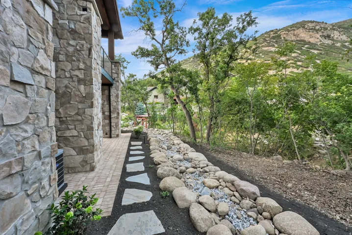 Stone exterior with a paver walkway and natural rock landscaping