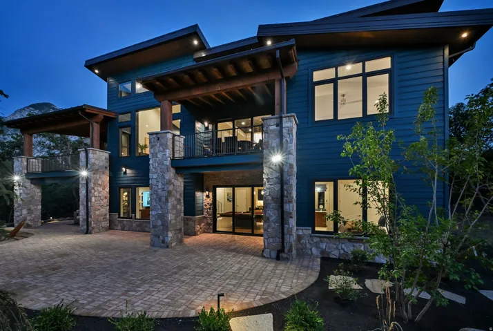 Contemporary multi-story residence featuring blue siding and stone columns