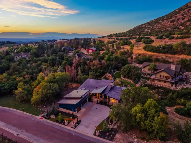 Contemporary residence featuring a metal roof, stone and siding exterior, multi-car garage, and a concrete driveway