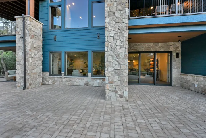 Expansive paver patio with a stone and wood-paneled exterior