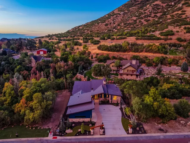 Contemporary residence featuring a striking metal roof, stone and siding exterior, and a paver driveway