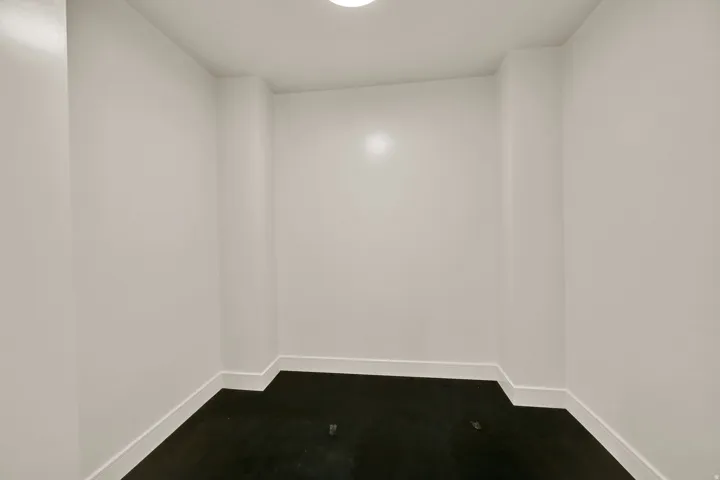 Compact interior space featuring white walls, dark flooring, and a flush-mount ceiling light fixture