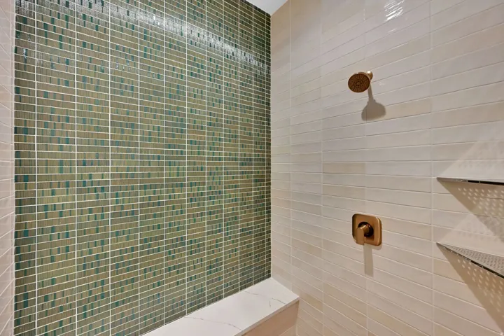 Shower featuring a mosaic tile accent wall, large format rectangular wall tiles, and brushed bronze fixtures