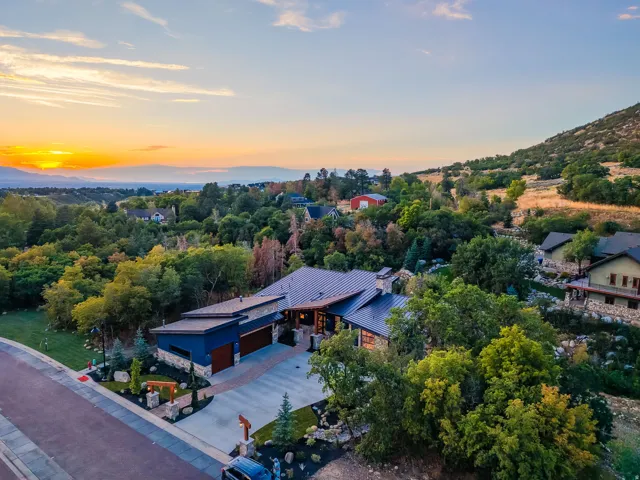 Contemporary residence featuring a dark metal roof, stone accents, and a large multi-car driveway