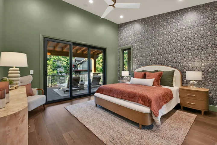 Spacious room featuring wood-finish flooring, a patterned accent wall, and a high ceiling with recessed lighting