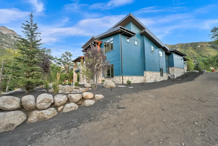 Modern exterior featuring blue horizontal siding and a stone foundation