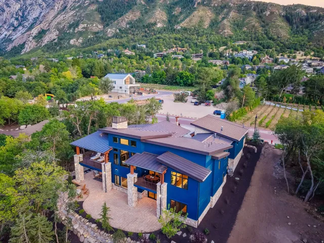 Contemporary mountain home featuring a vibrant blue exterior, a metal roof, and stone pillars