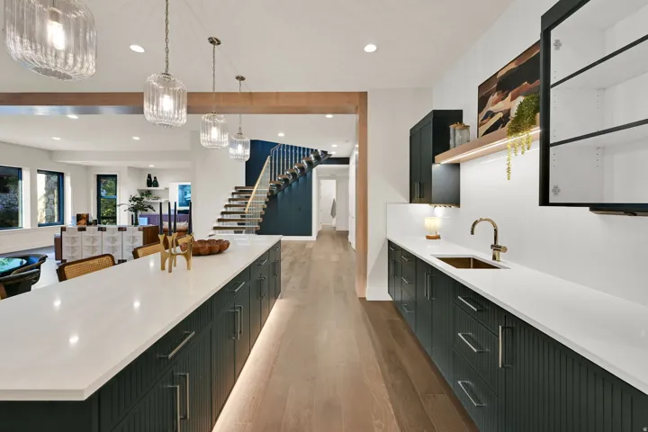 Expansive kitchen island and wet bar featuring white countertops and dark cabinetry