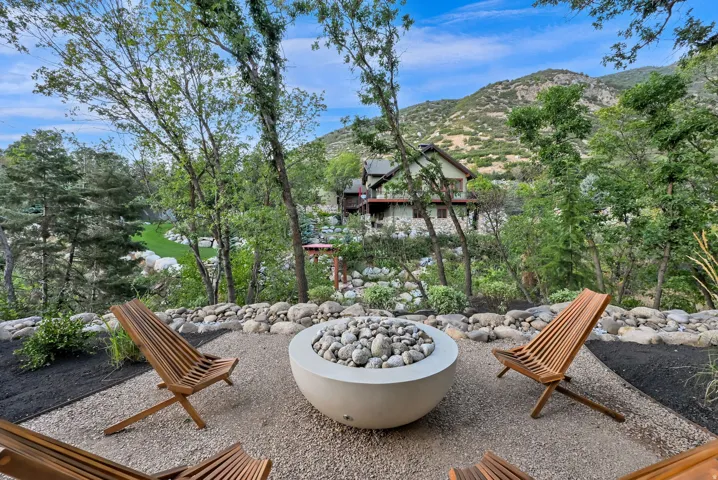 Outdoor living space featuring a concrete fire pit, gravel ground cover, and surrounding rock landscaping