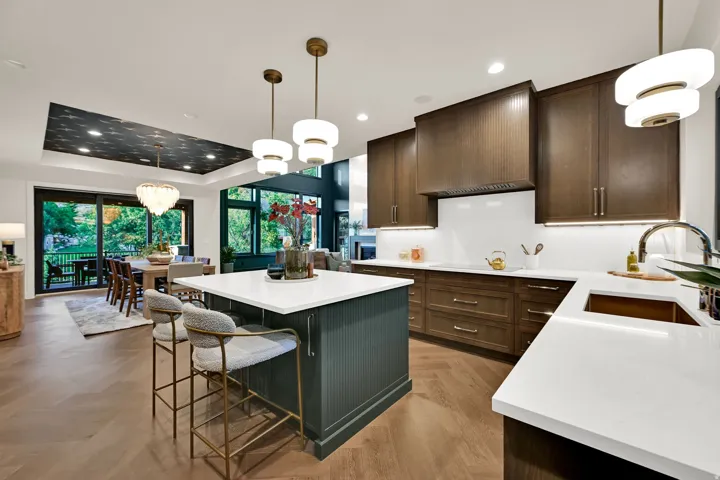 Open-concept kitchen featuring an island with seating, dark wood-finish cabinetry, white countertops, herringbone wood-finish flooring, and pendant lighting