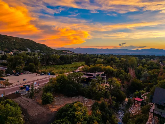 Expansive landscape featuring distant mountains, lush green trees, and a visible property with a red-roofed structure