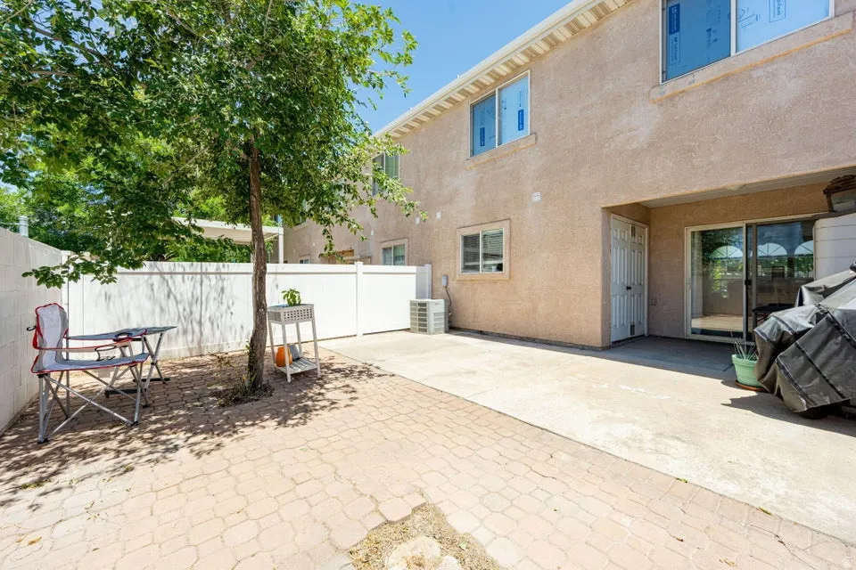 Private outdoor space featuring a paved patio, mature tree, and privacy fence