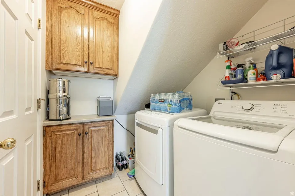 Dedicated laundry area featuring a tile floor, wood-finish cabinetry, a built-in countertop, and wire shelving