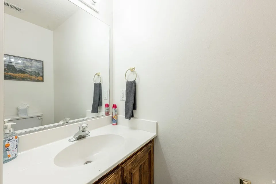 Bathroom vanity featuring a white countertop with an integrated oval sink, chrome faucet, and wood-finish cabinetry