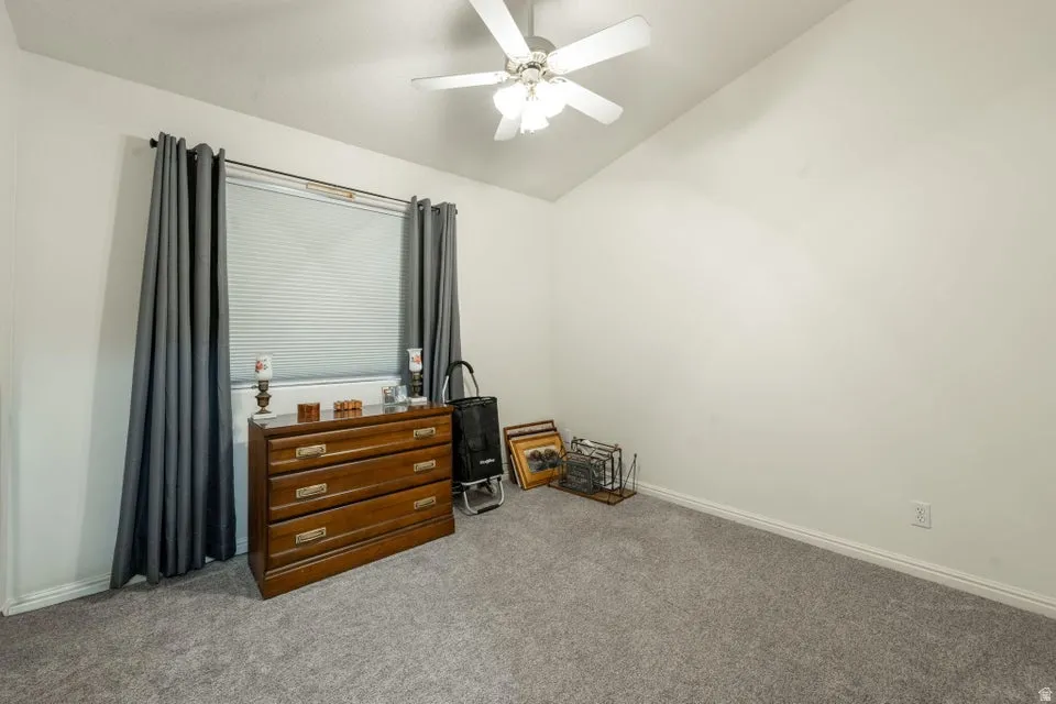 Interior room featuring vaulted ceilings, a window with horizontal blinds, and grey carpeting