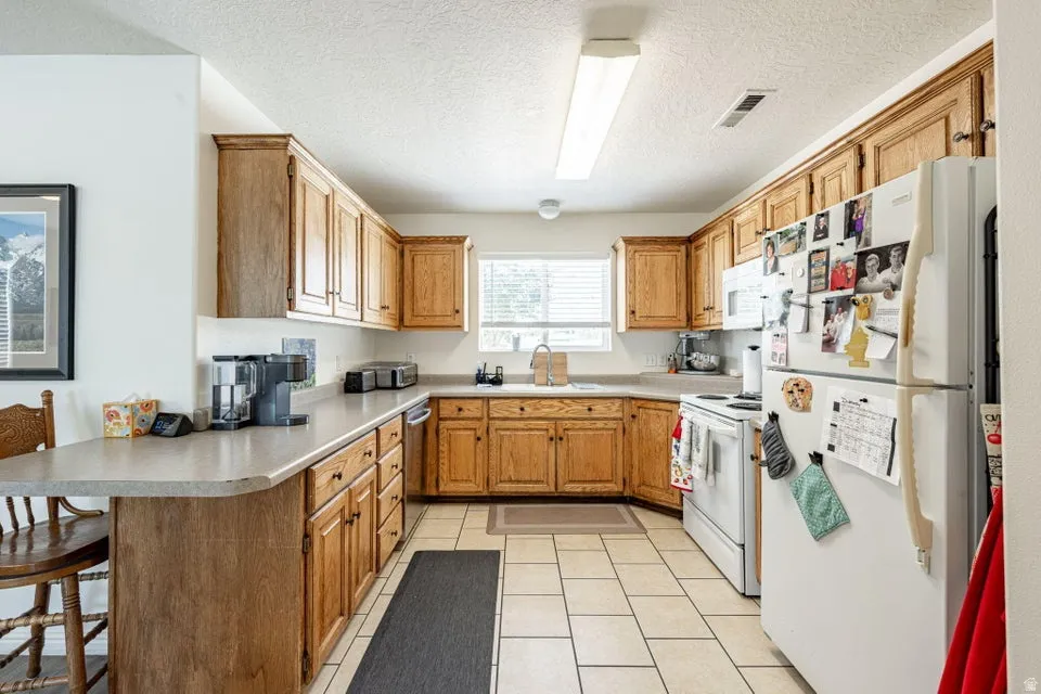 Kitchen featuring extensive wood cabinetry, L-shaped countertops, and tile flooring