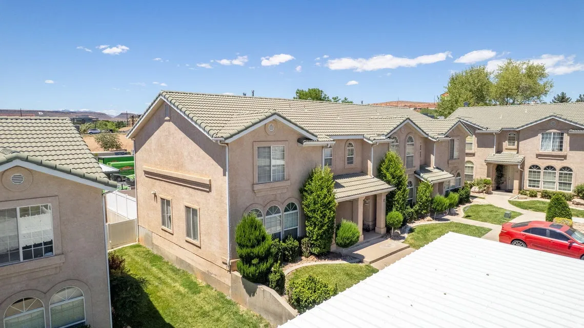 Contemporary stucco exterior featuring multiple arched windows, prominent entryways, gabled roofs, and manicured landscaping