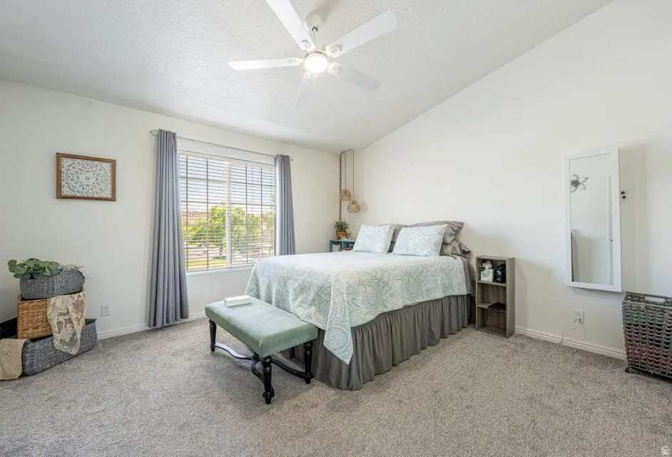 Spacious room featuring neutral carpeting, a large window with horizontal blinds, and a white ceiling fan with integrated lighting