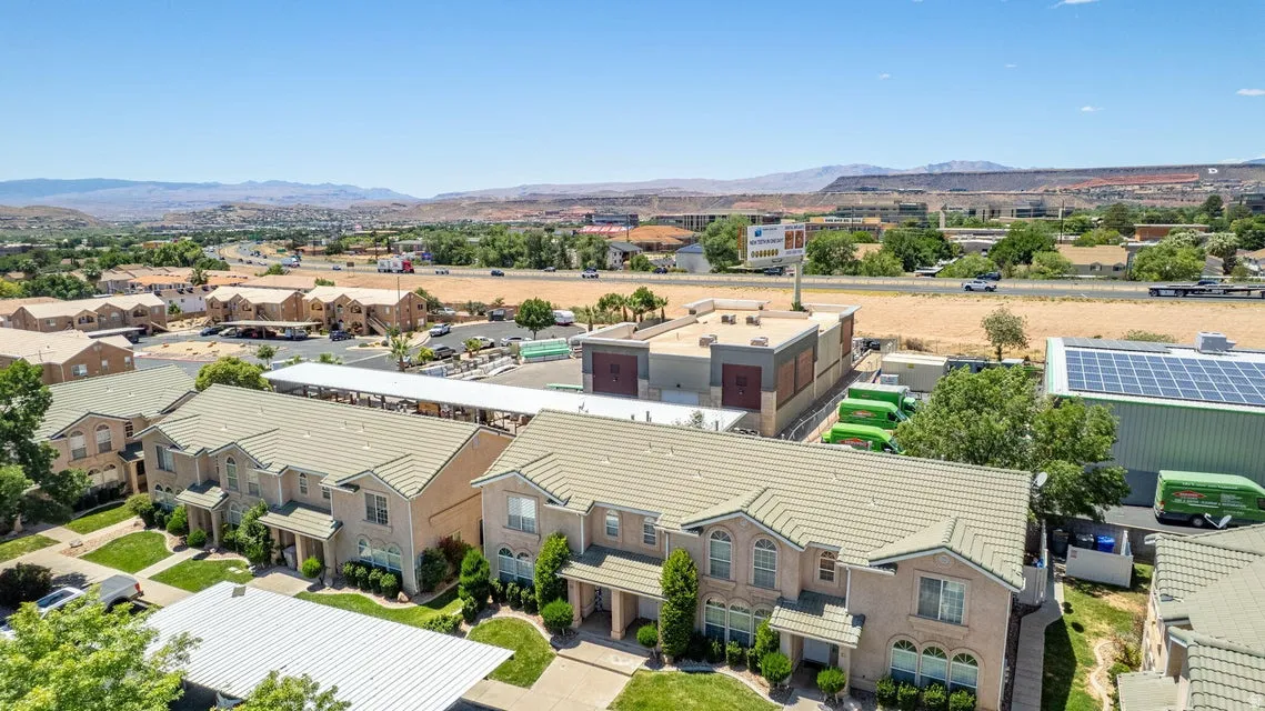 Townhome-style residences featuring light-toned exterior siding, gabled roofs, covered front entrances, and landscaped front yards