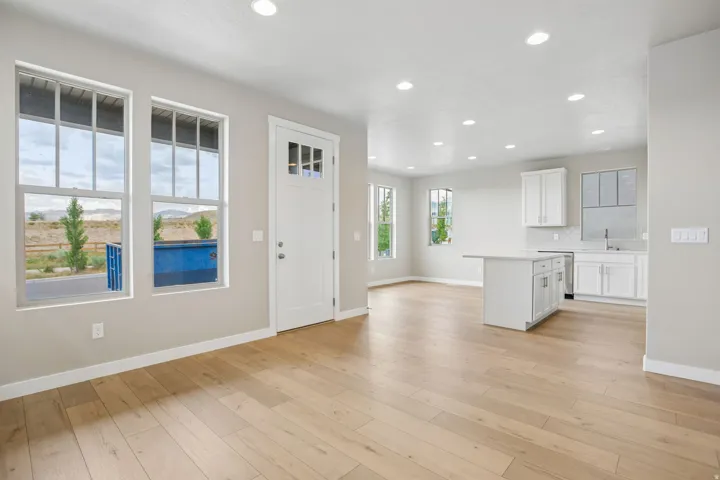 Open-concept living space featuring light wood-finish flooring, recessed lighting, and a kitchen with white cabinetry and a central island
