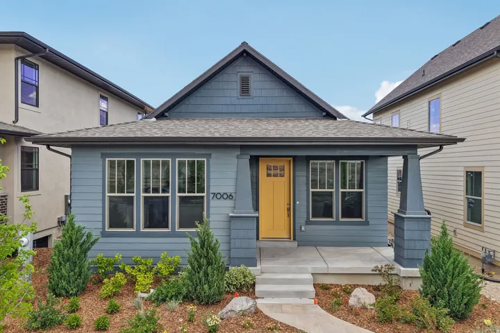 Contemporary home with blue siding, a covered porch, and a bright yellow entry door