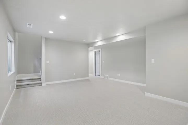 Spacious carpeted room featuring recessed lighting, a window, white trim, and light gray painted walls