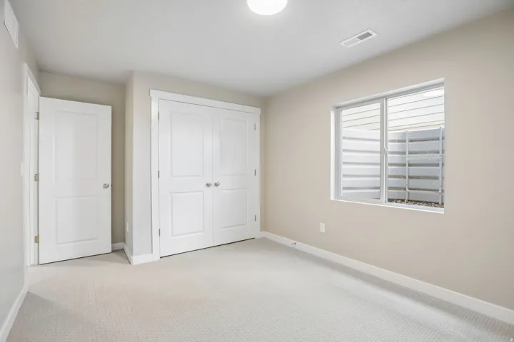 Carpeted room with a double bifold closet, a single window, and neutral-toned walls