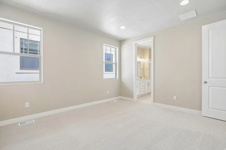 Light-filled room featuring neutral-toned walls, recessed lighting, and soft carpet flooring