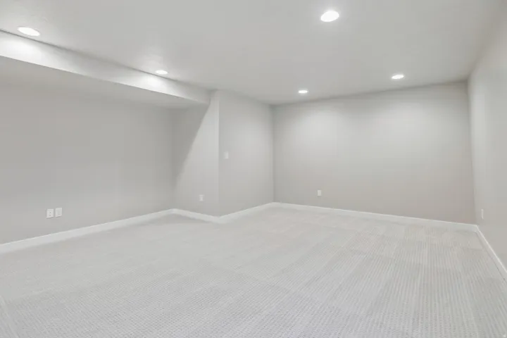 Spacious room featuring light gray walls, recessed lighting, and a neutral carpeted floor
