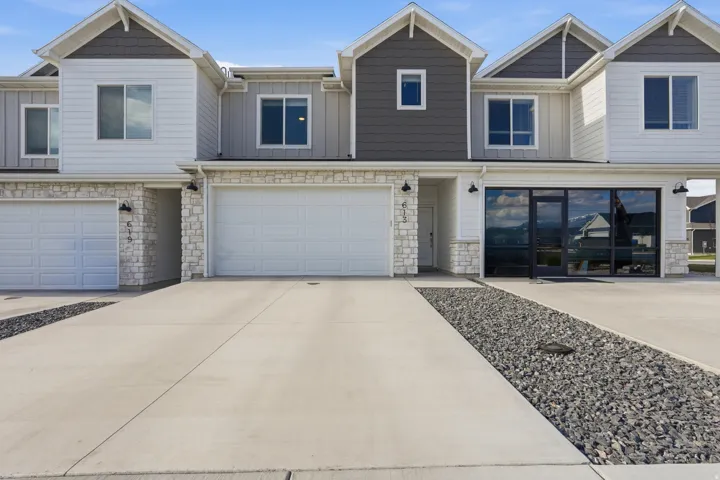 Modern townhome exterior featuring light-colored stone accents, horizontal siding, and dark shake siding