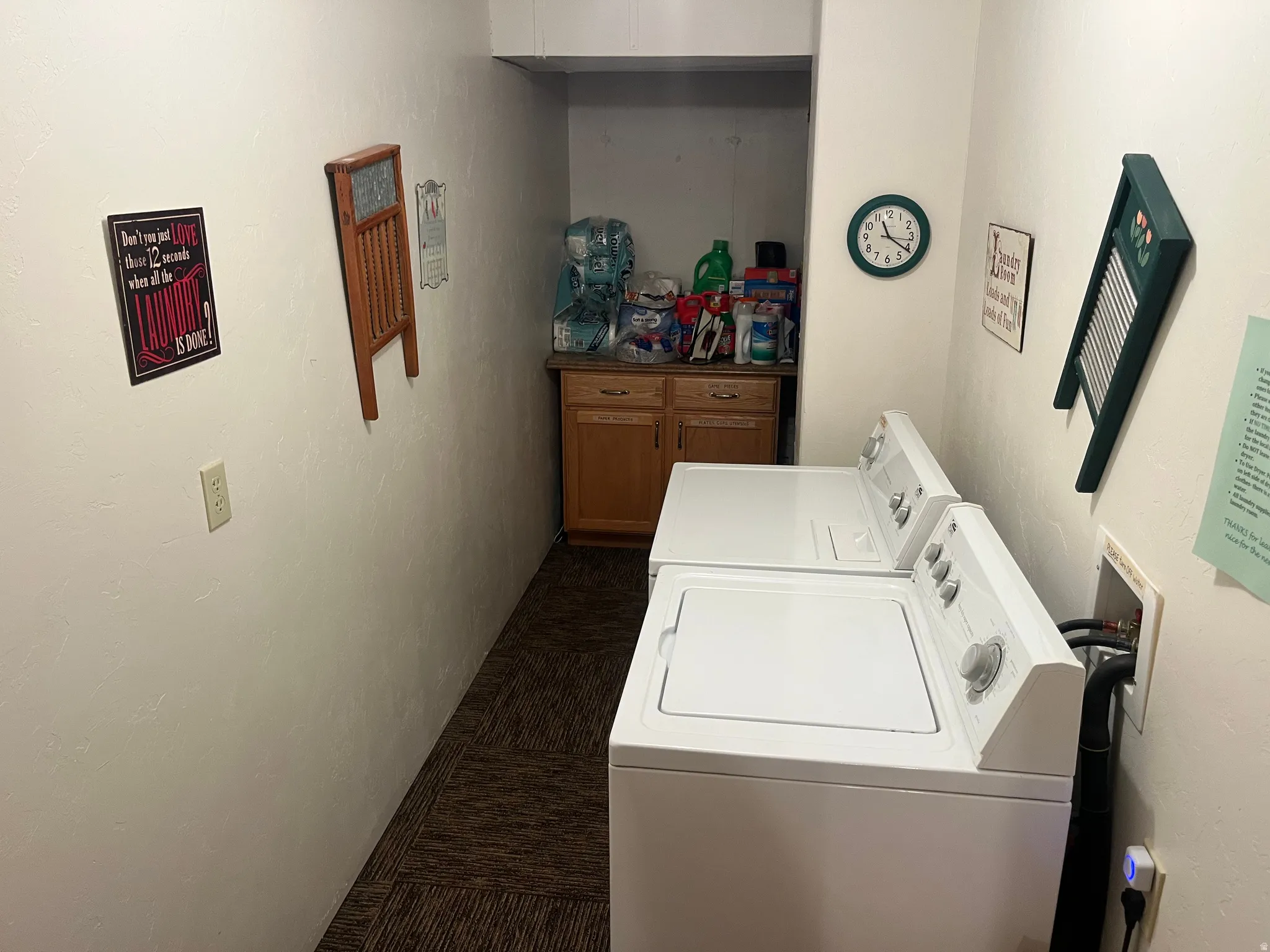 Dedicated laundry area featuring a white top-load washing machine and dryer, wood-finish cabinetry, a built-in countertop, and patterned carpet flooring