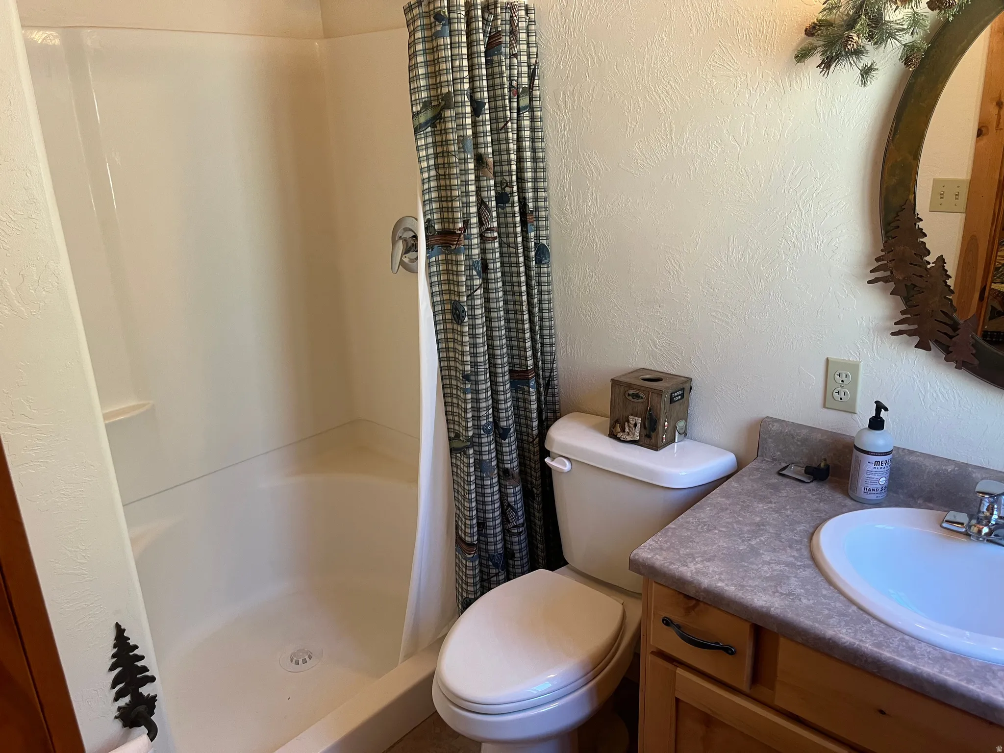 Full bathroom featuring a white tub-shower combination, a vanity with a laminate countertop, and natural wood cabinetry with dark hardware