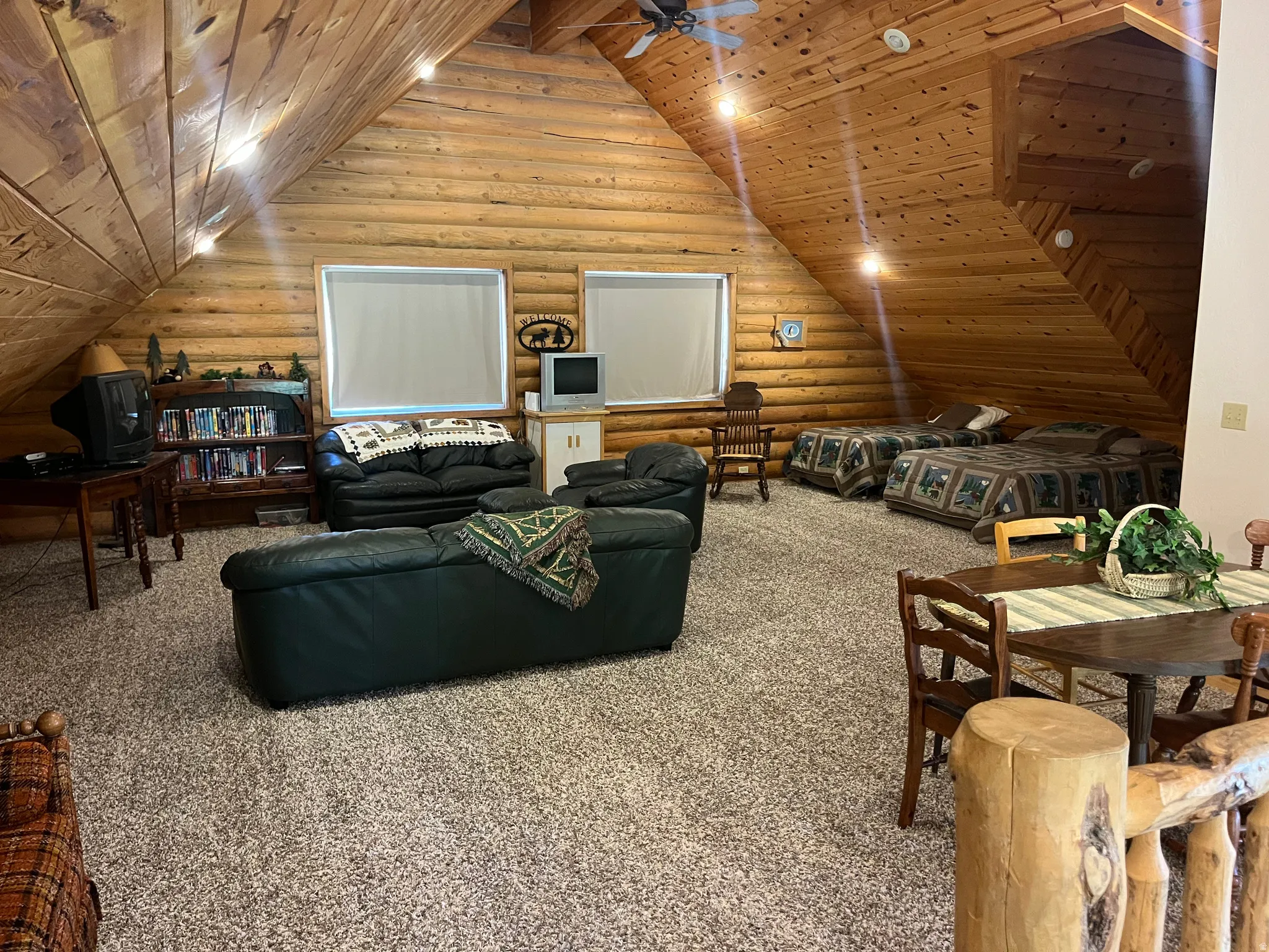Spacious attic space featuring tongue-and-groove wood paneling on the ceiling and log walls