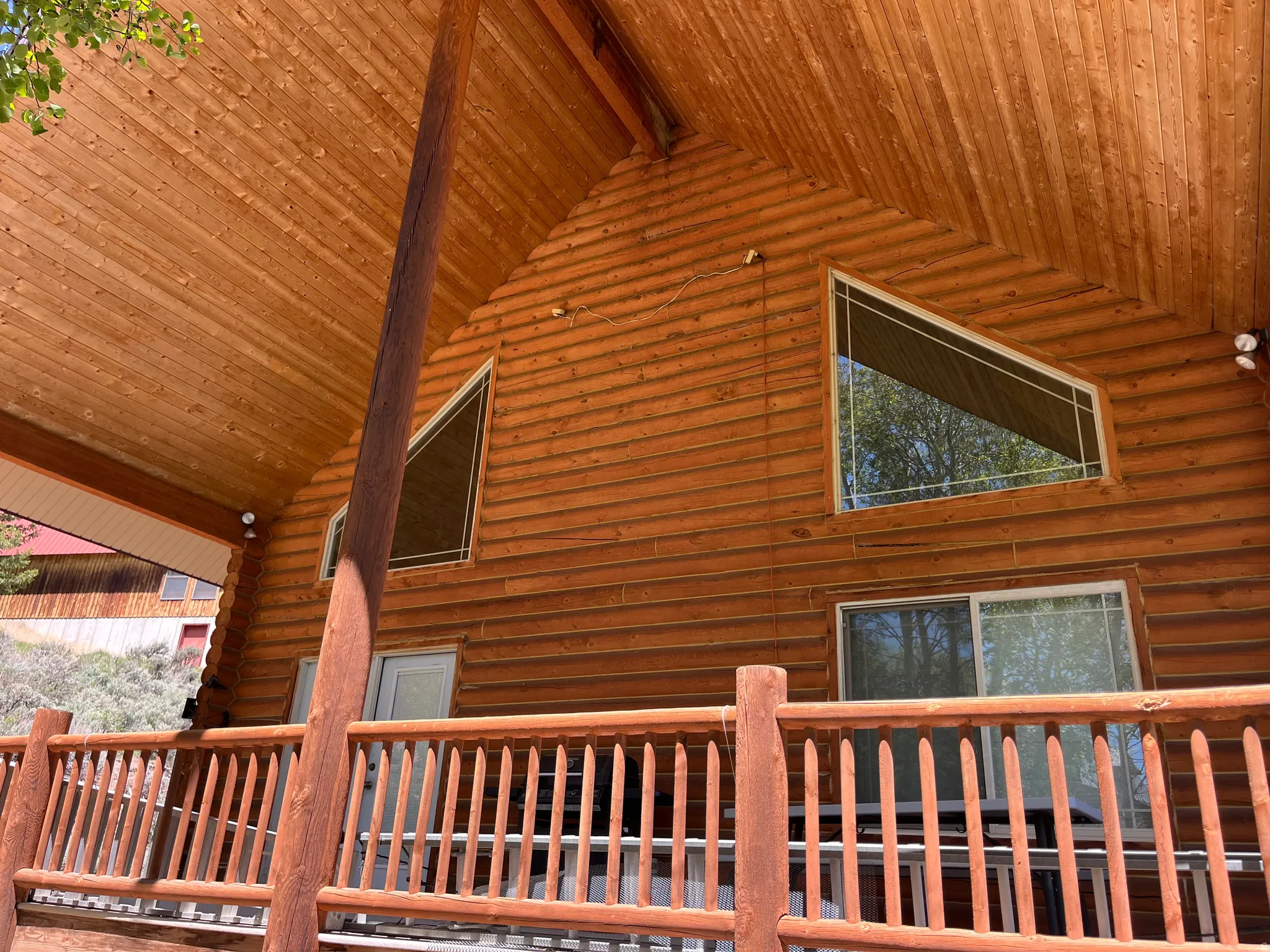 Log cabin exterior featuring a covered porch with a wood railing and support beam