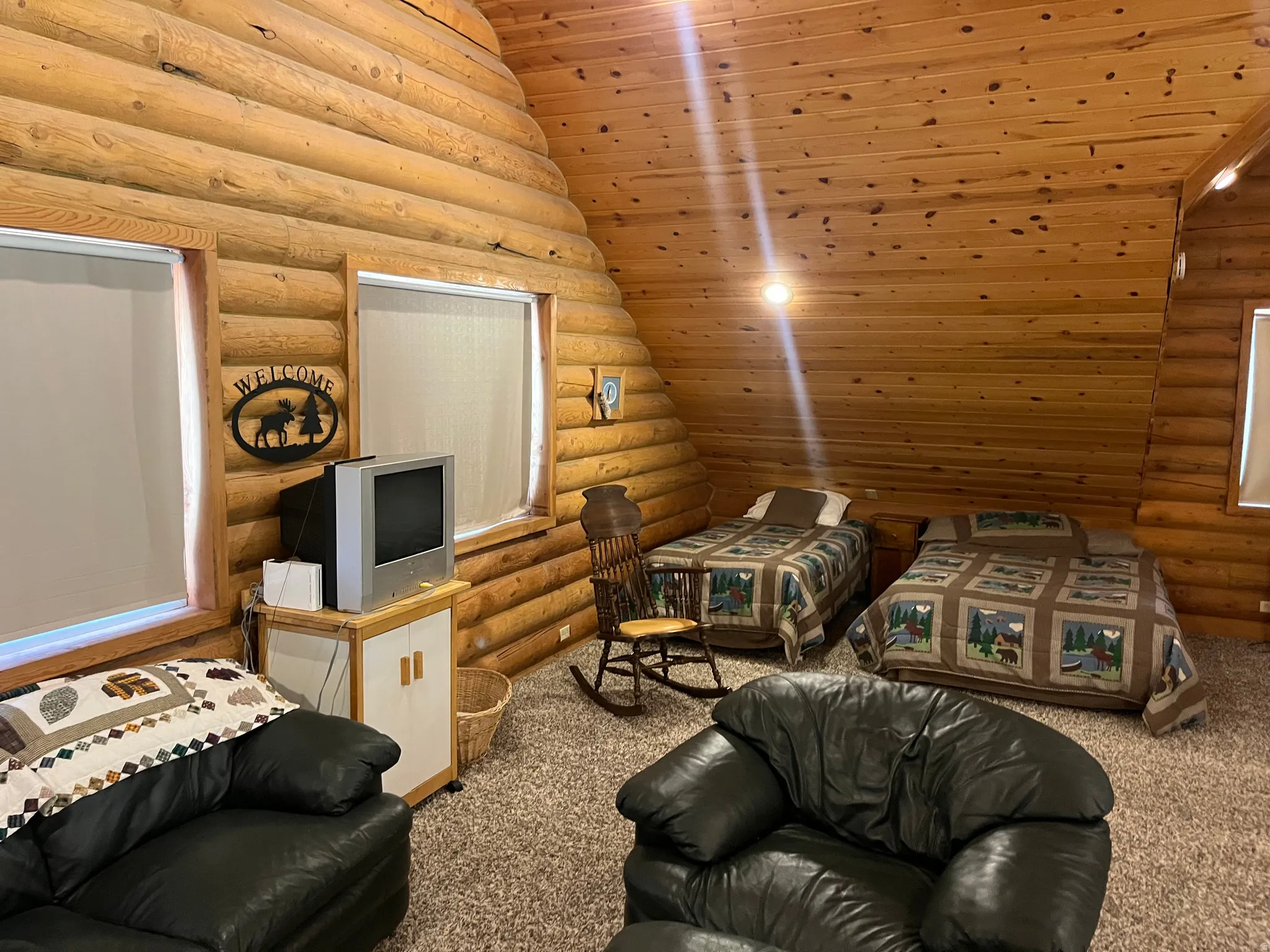 Wood-paneled walls and ceiling featuring two windows with roller shades, recessed lighting, and carpeting throughout