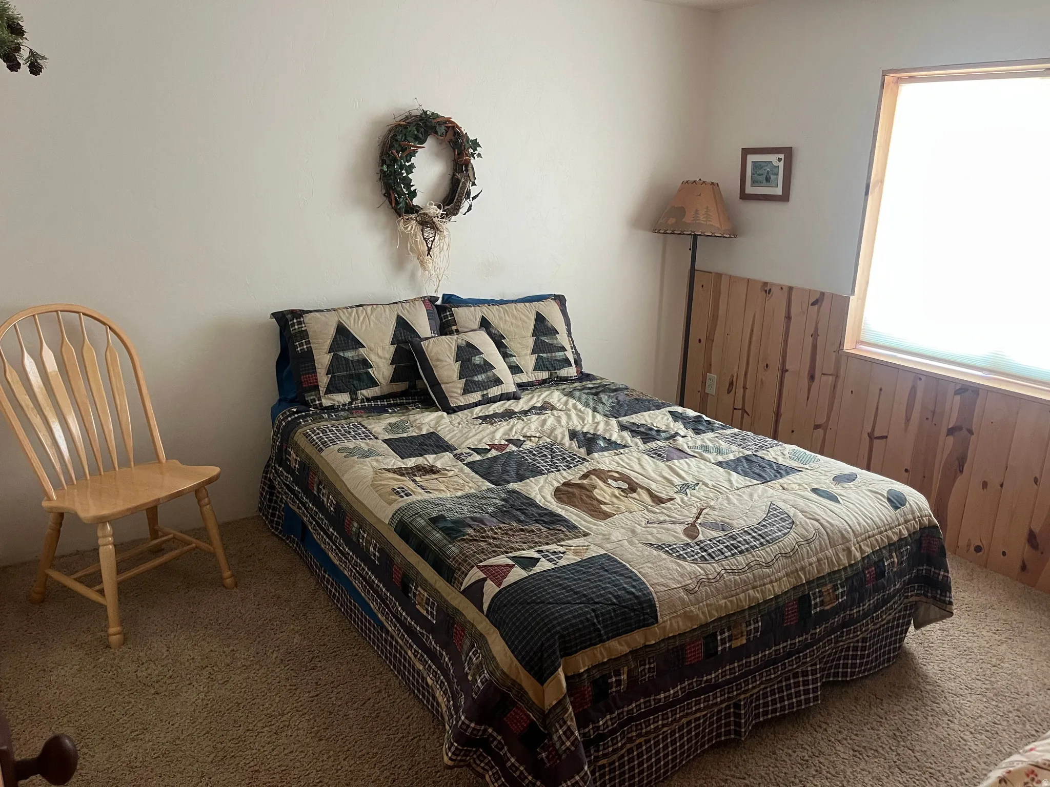 Bedroom featuring carpet flooring, natural wood paneling, and a wood-framed window