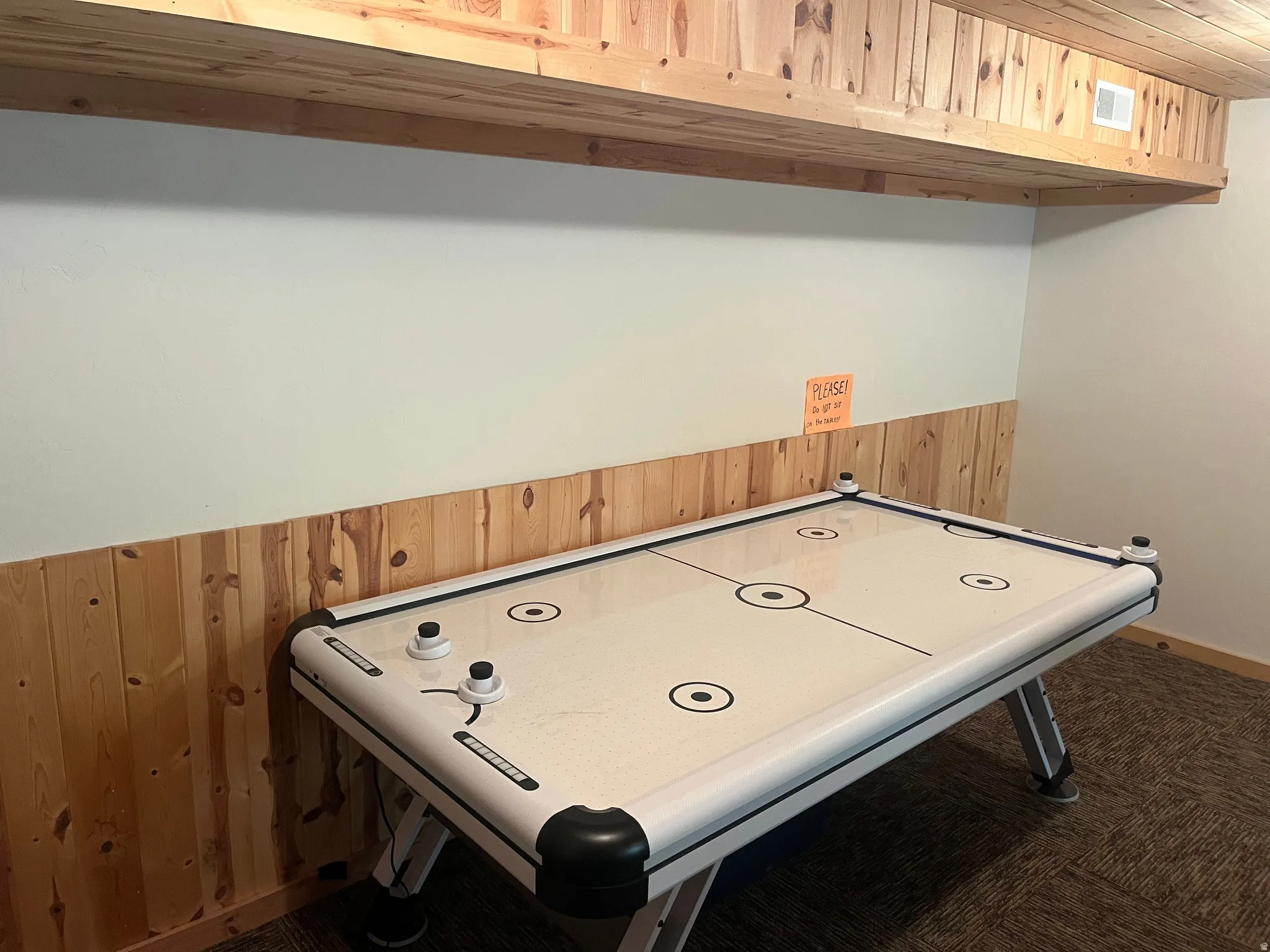 Recreation space featuring wood paneling, wood-finish ceiling, and textured carpet flooring