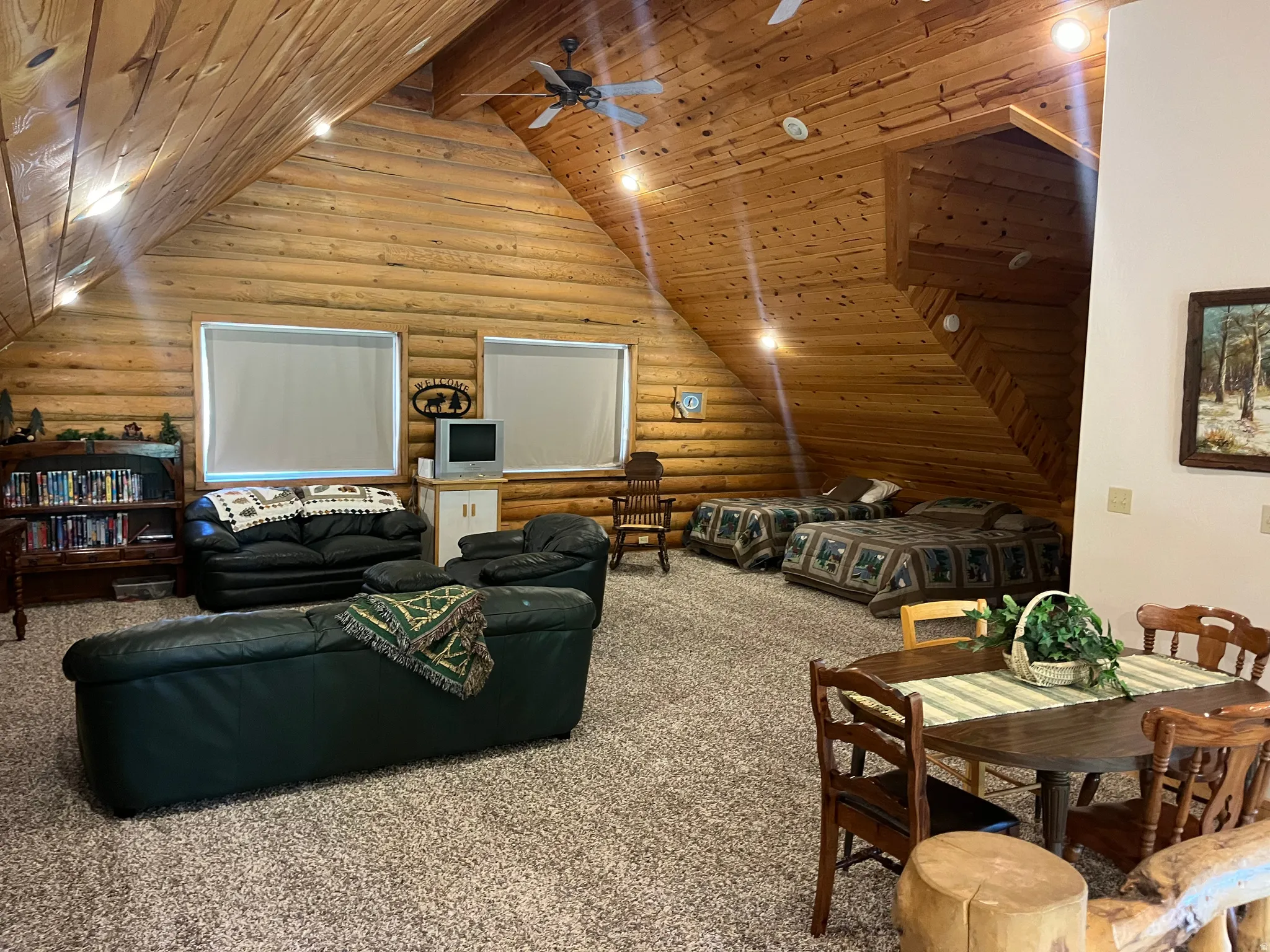 Spacious open area featuring log walls, vaulted wood plank ceilings, recessed lighting, and ceiling fan