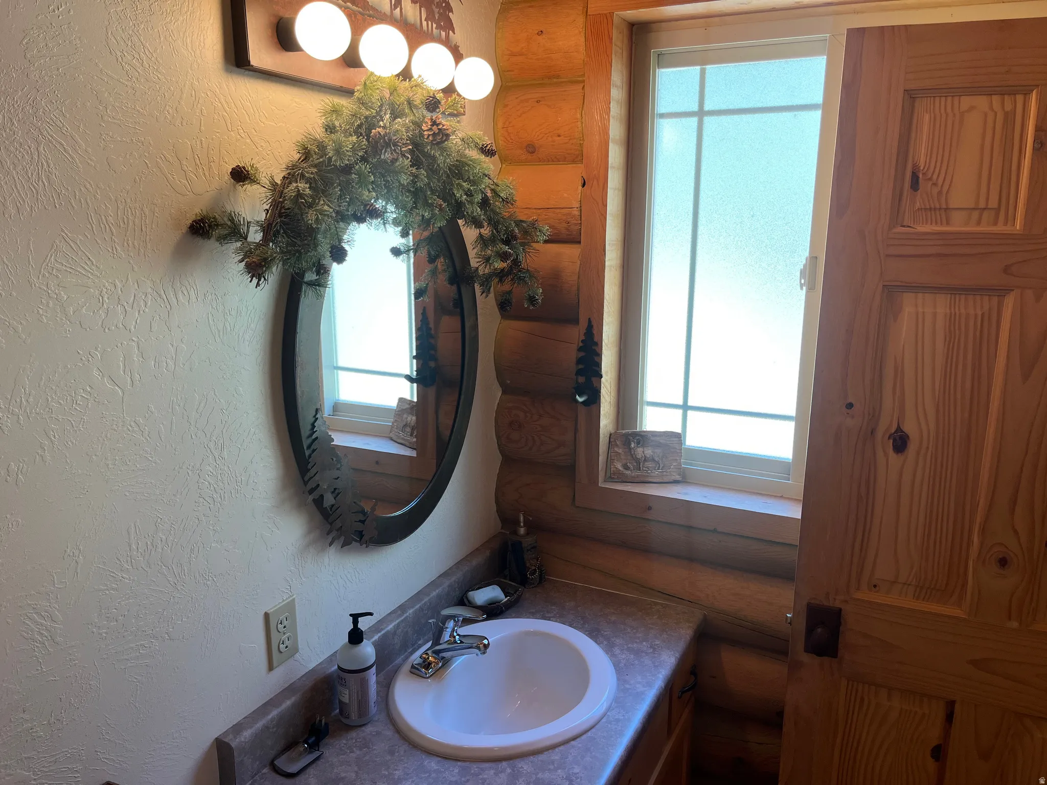 Bathroom vanity featuring a white oval sink, chrome faucet, and a laminate countertop