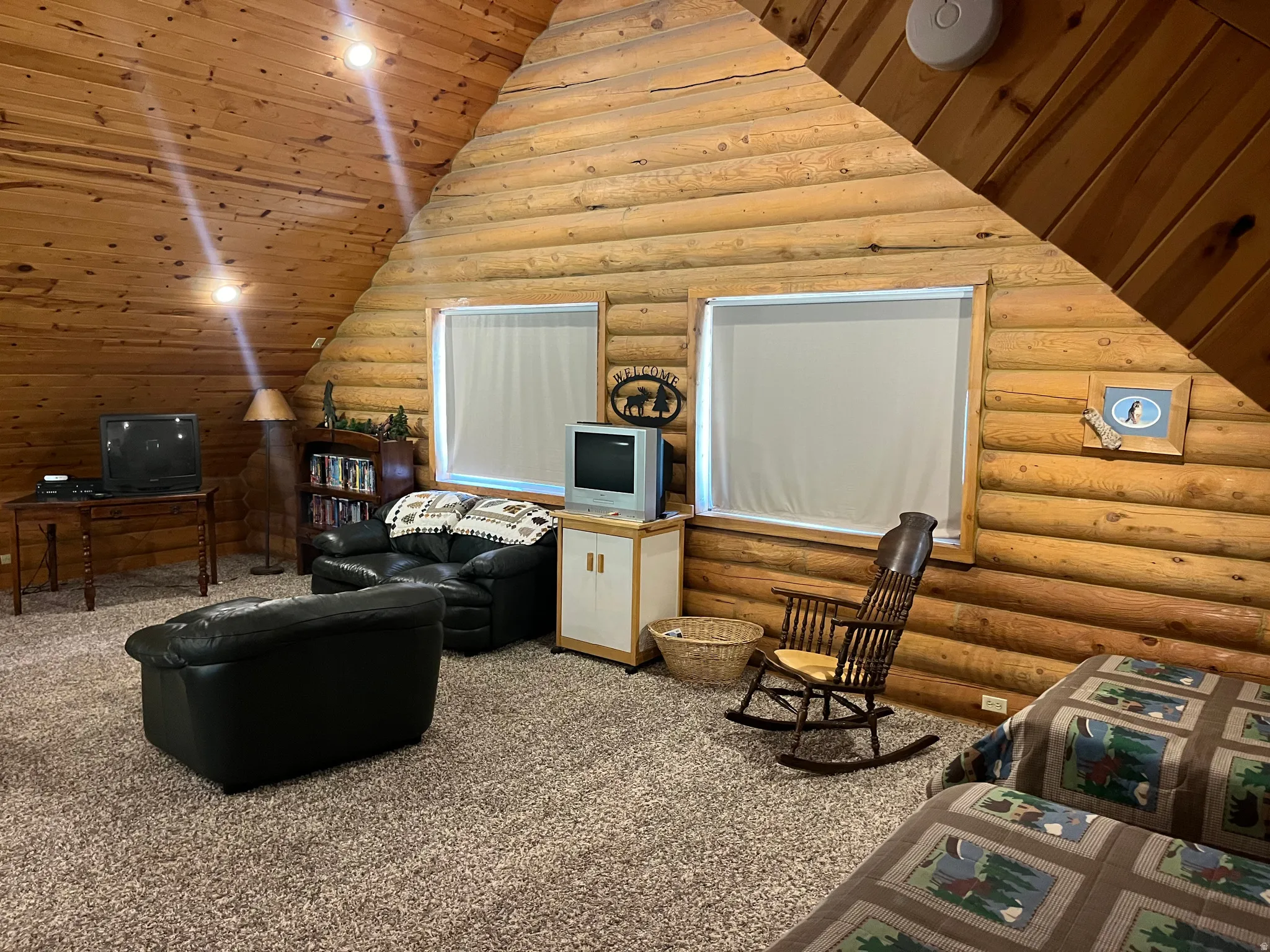 Rustic interior featuring log wall construction and a vaulted wood-paneled ceiling