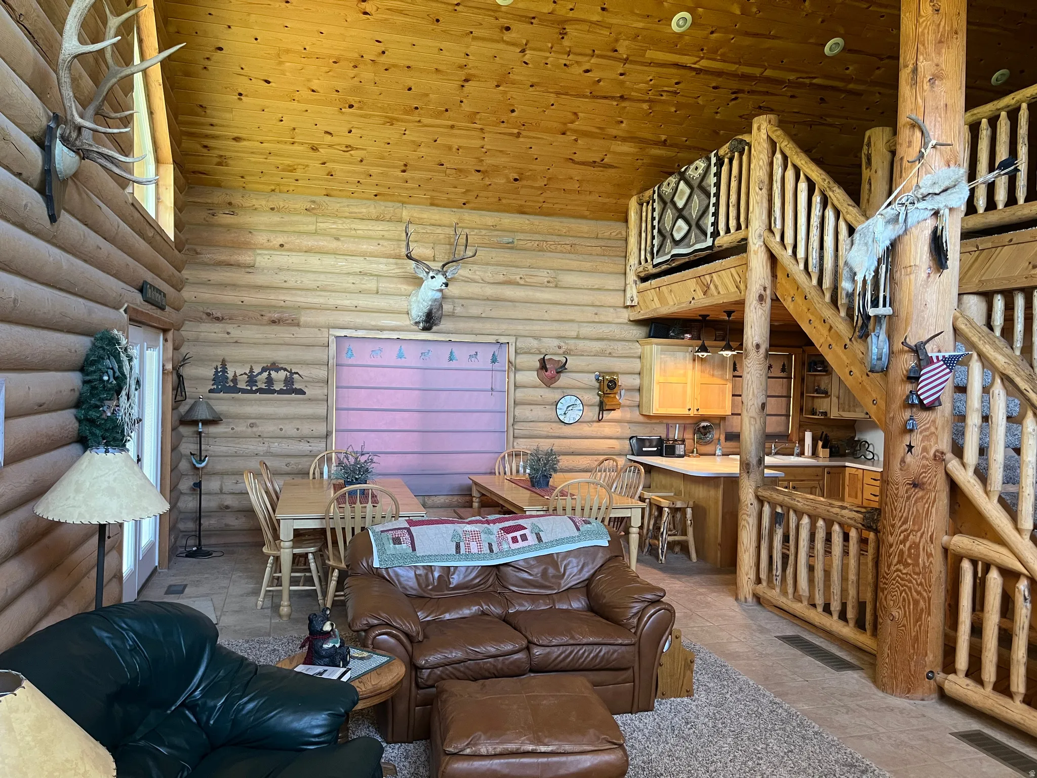 Expansive great room featuring log walls and a vaulted wood-finish ceiling