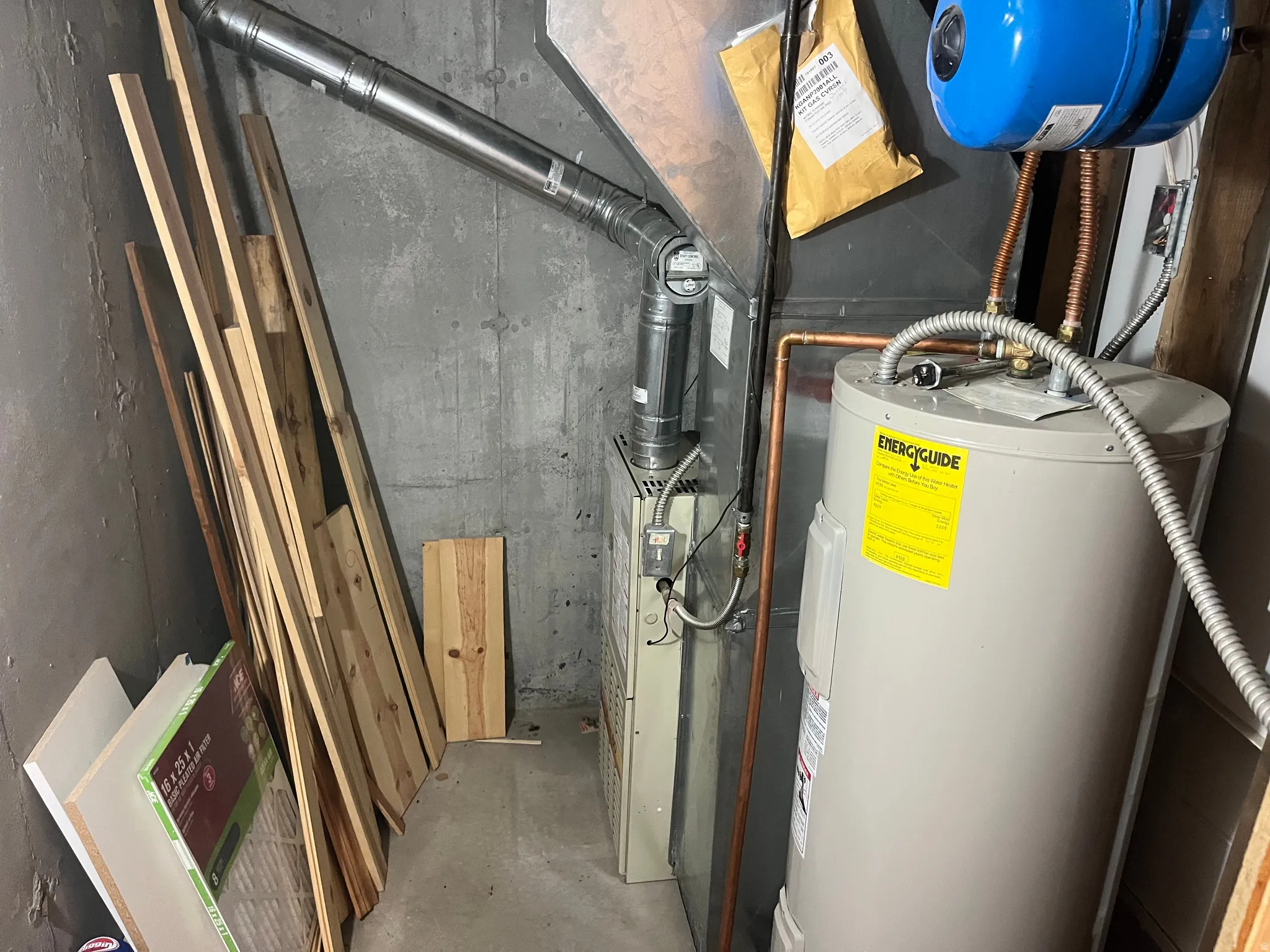 Utility area featuring a water heater, furnace, and exposed ductwork