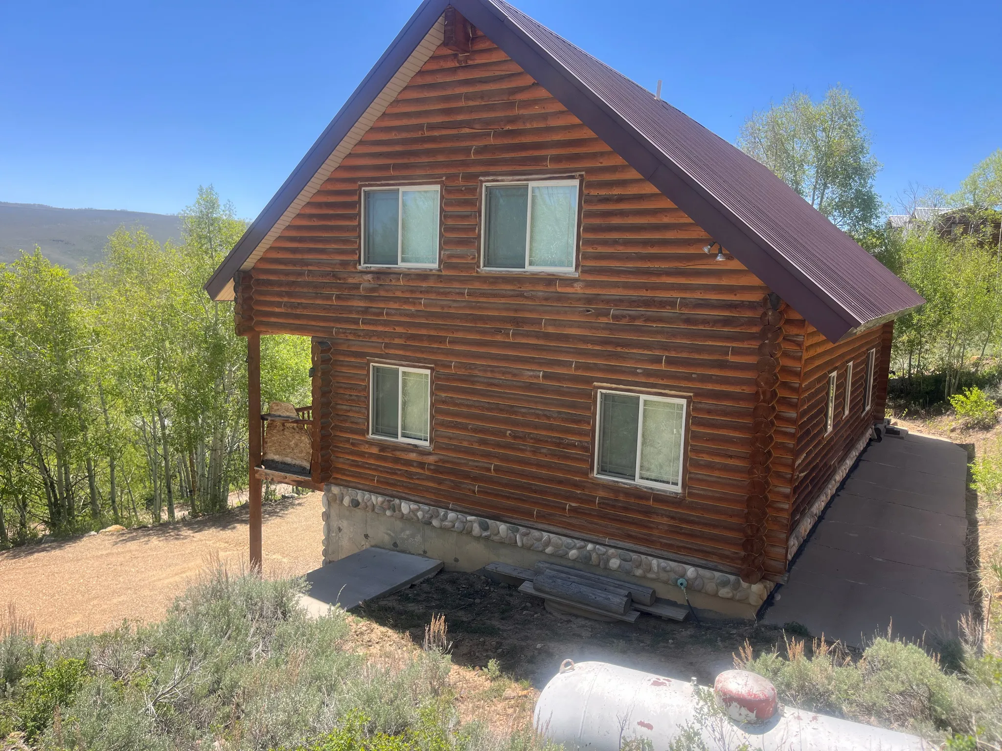 Two-story log cabin exterior featuring a brown metal roof
