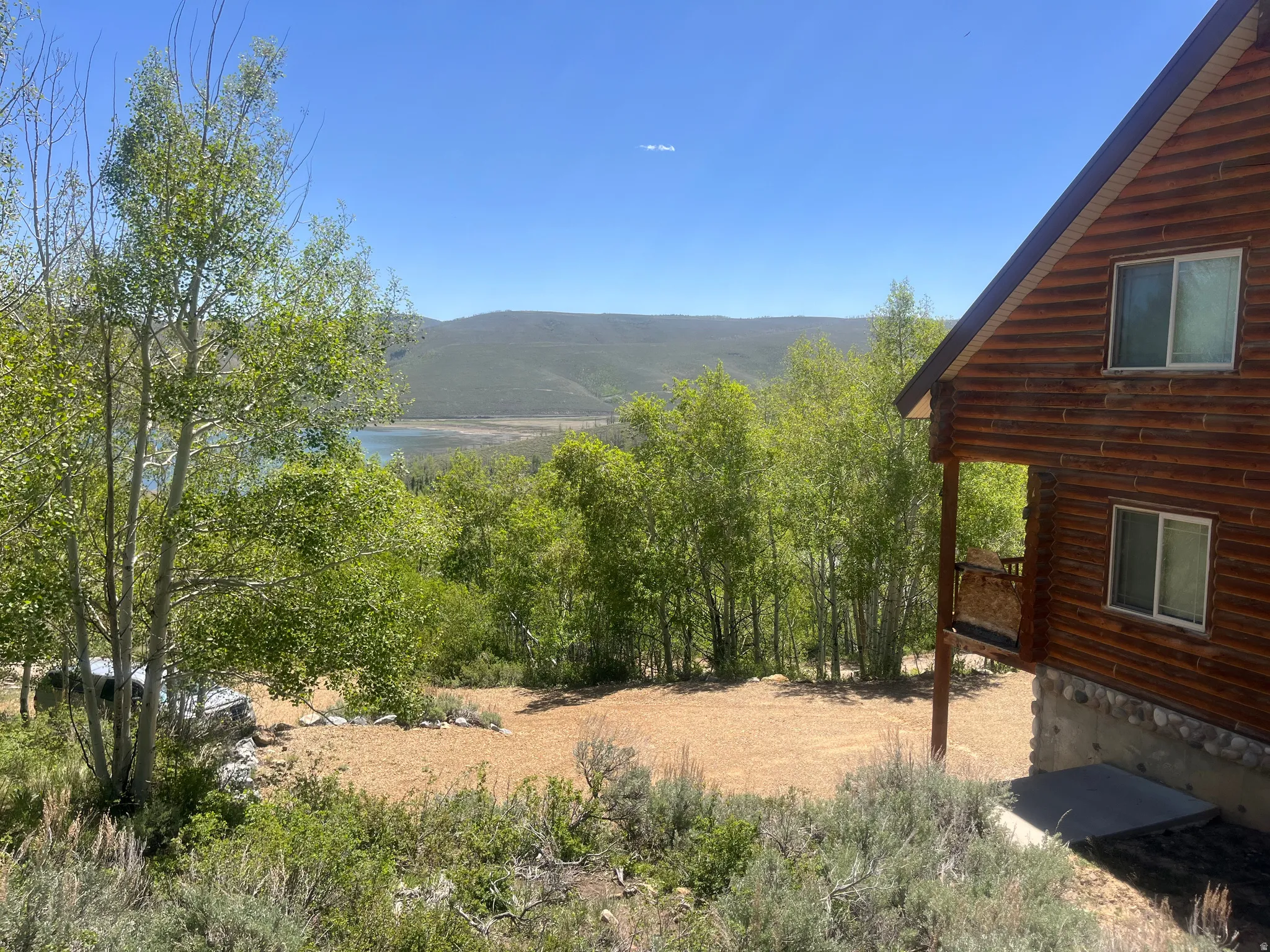 Log-sided exterior with a natural stone foundation, featuring multiple windows and a covered balcony