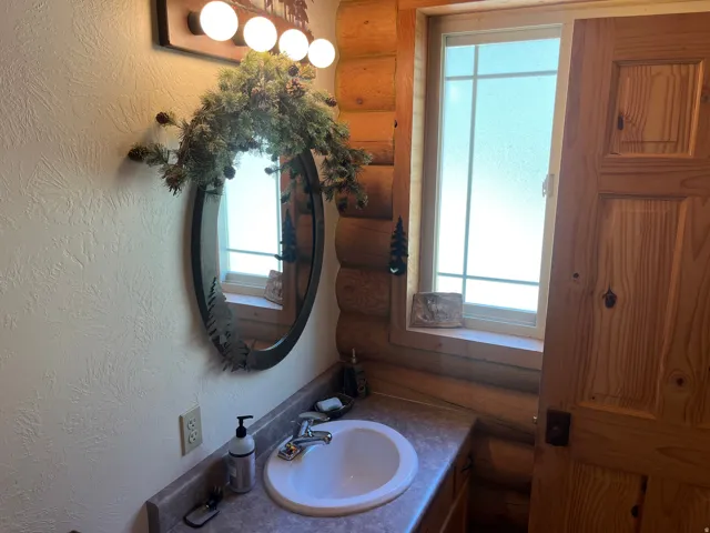 Bathroom vanity featuring a white oval sink, chrome faucet, and a laminate countertop