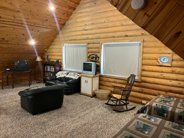 Rustic interior featuring log wall construction and a vaulted wood-paneled ceiling