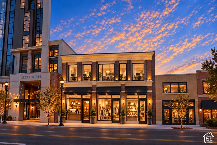 Multi-story brick exterior featuring expansive storefront windows, architectural cornices, integrated building illumination, and black metal-framed glass entry doors