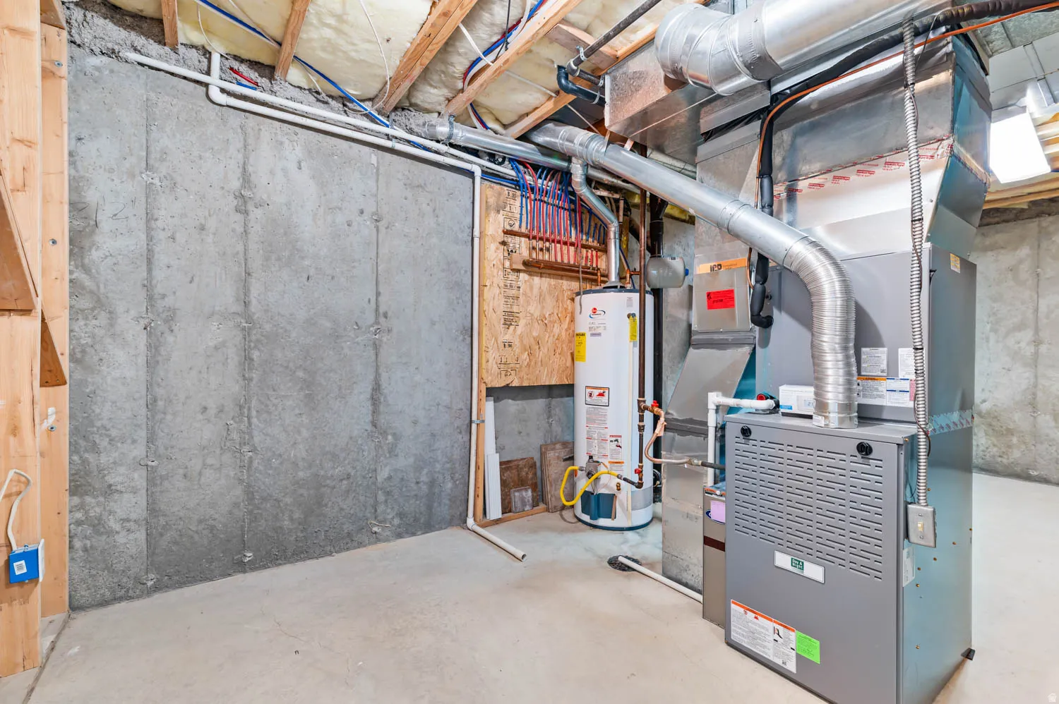Basement utility area featuring a concrete foundation, exposed ceiling joists, a water heater, and a furnace with ductwork