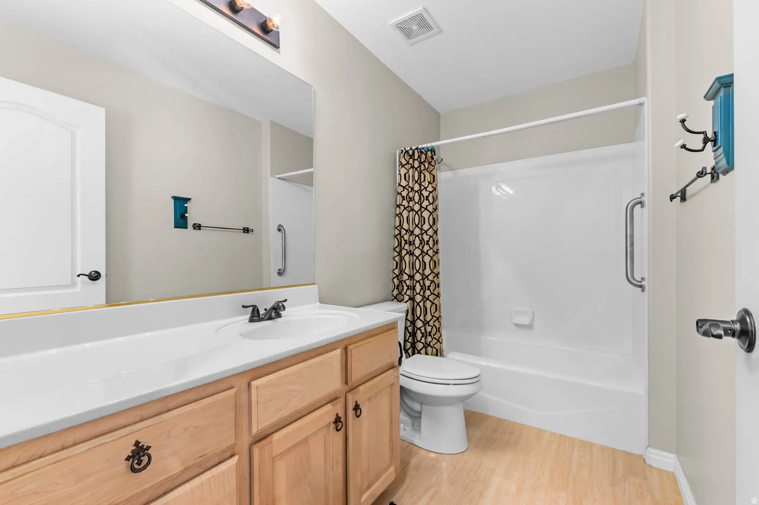 Bathroom featuring a full vanity with wood-finish cabinetry, a single basin sink, and a large wall-mounted mirror